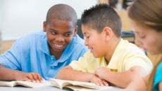 A transracially adopted boy joking with a friend in class