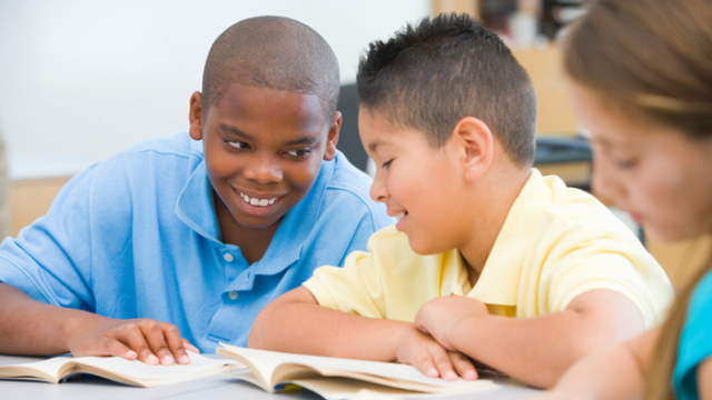 A transracially adopted boy joking with a friend in class