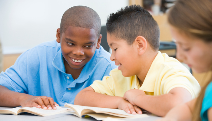 A transracially adopted boy joking with a friend in class