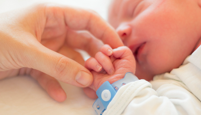 parent holding newborn baby's hand in the hospital after a "stork drop" last-minute adoption placement