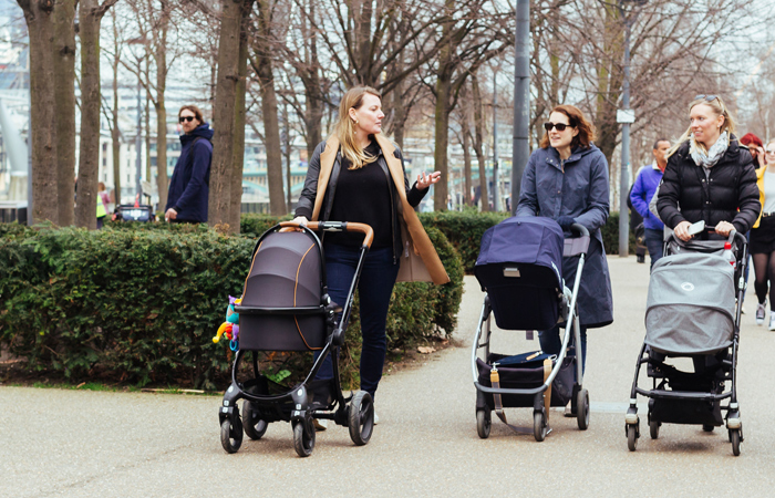 Three mothers pushing strollers in the city, one asking a nosy adoption question